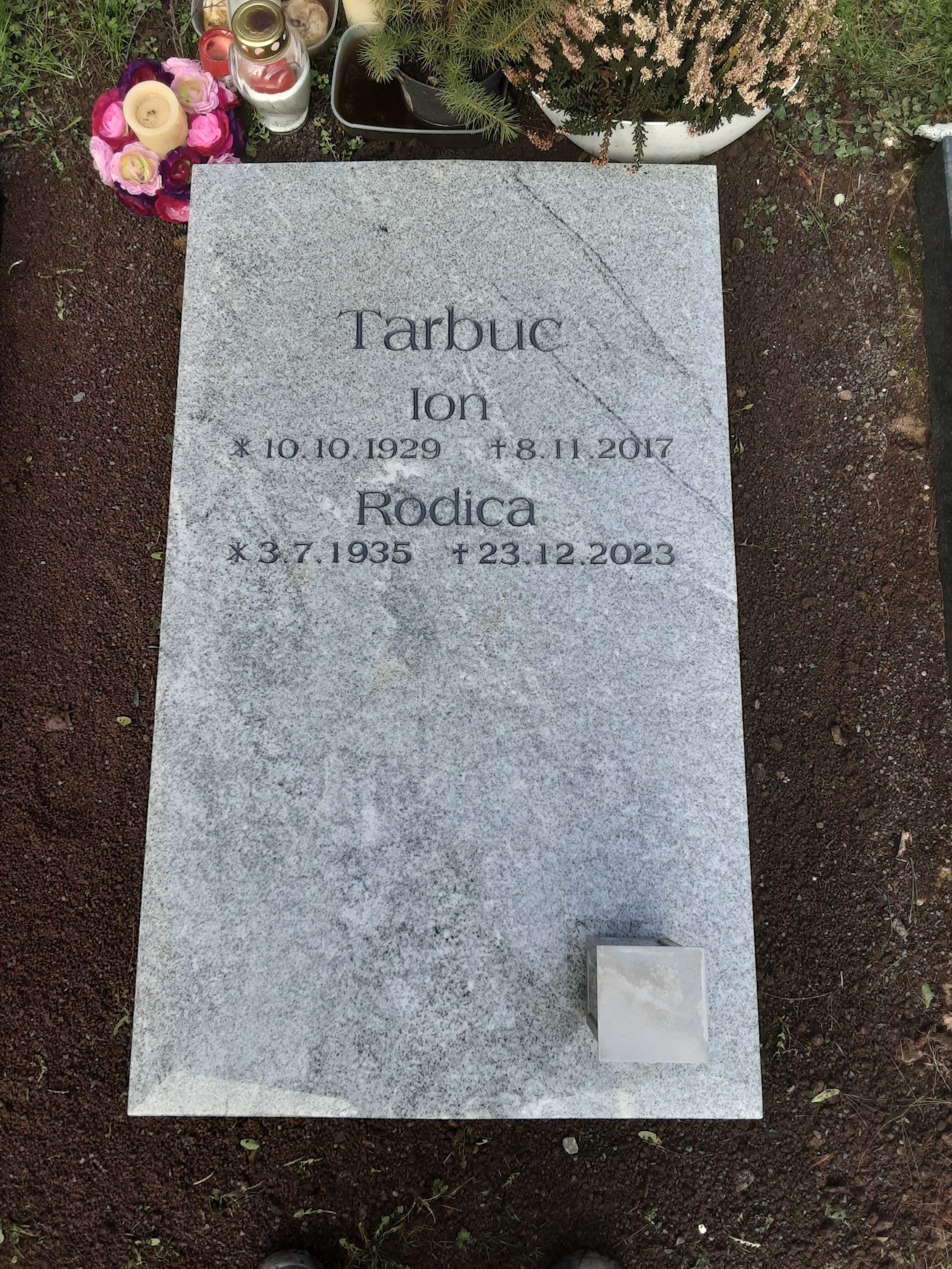 Grabstein mit dem Namen Farbuc, Geburts- und Sterbedatum, Blumen und einer kleinen Markierung.