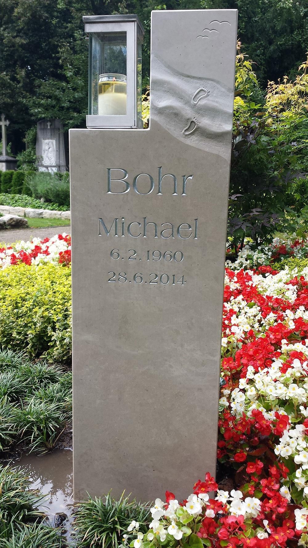 Ein Grabstein auf einem Friedhof, umgeben von Blumen.