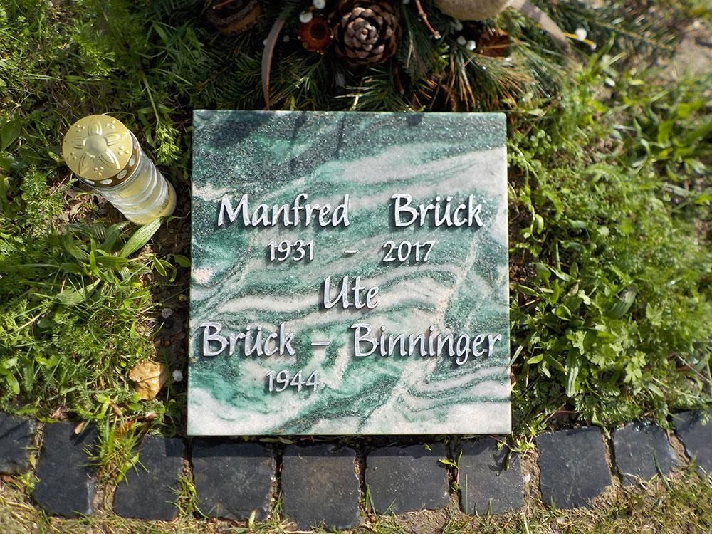 Ein Grabstein für Manfred Brick liegt im Gras.