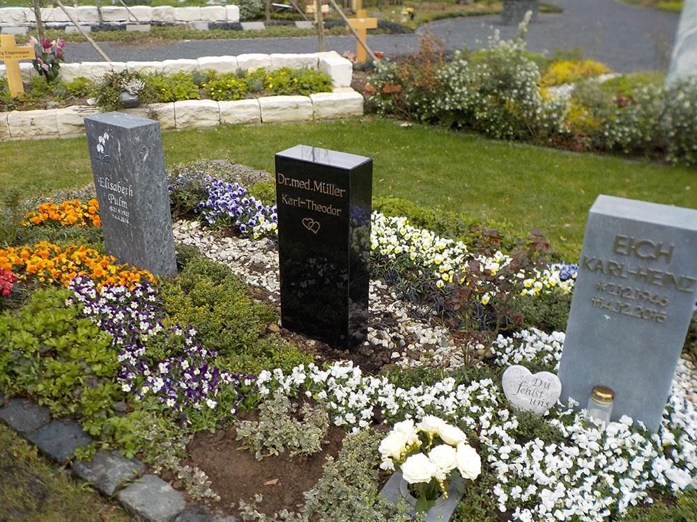 Zwei Gräber auf einem Friedhof mit Blumen und Kerzen