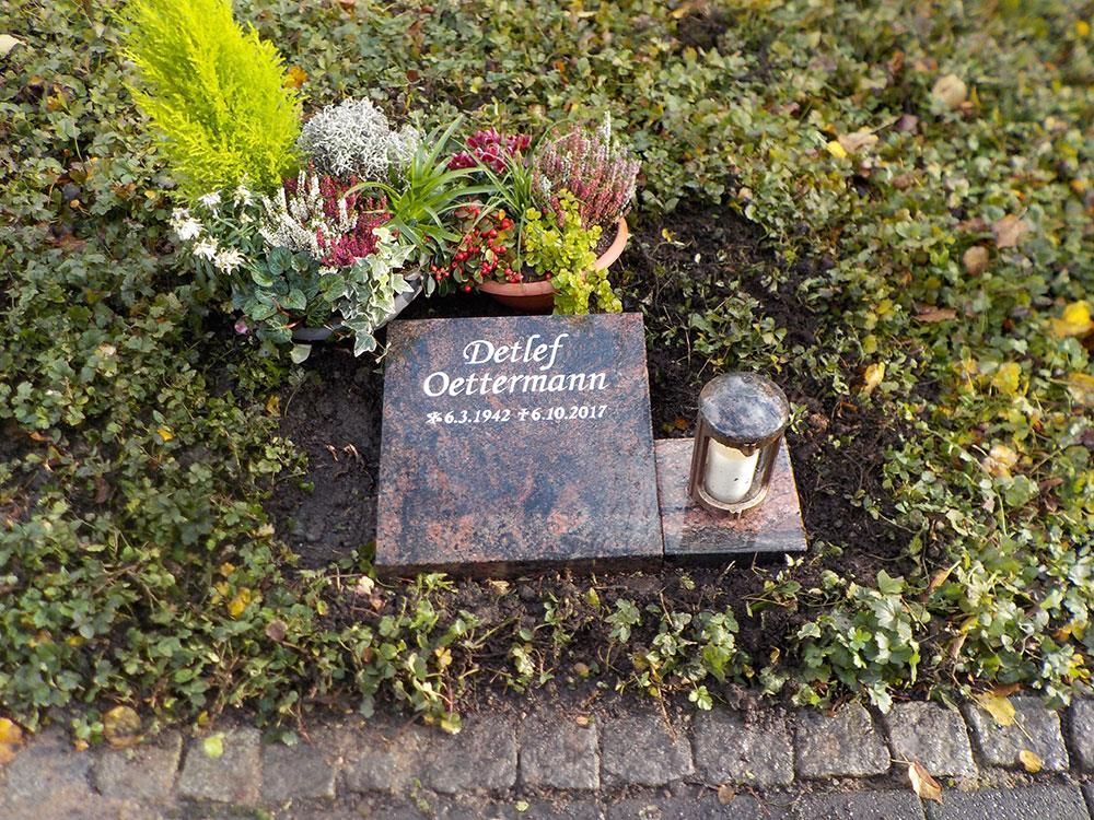 Ein Grab mit Blumen und einer Kerze darauf.