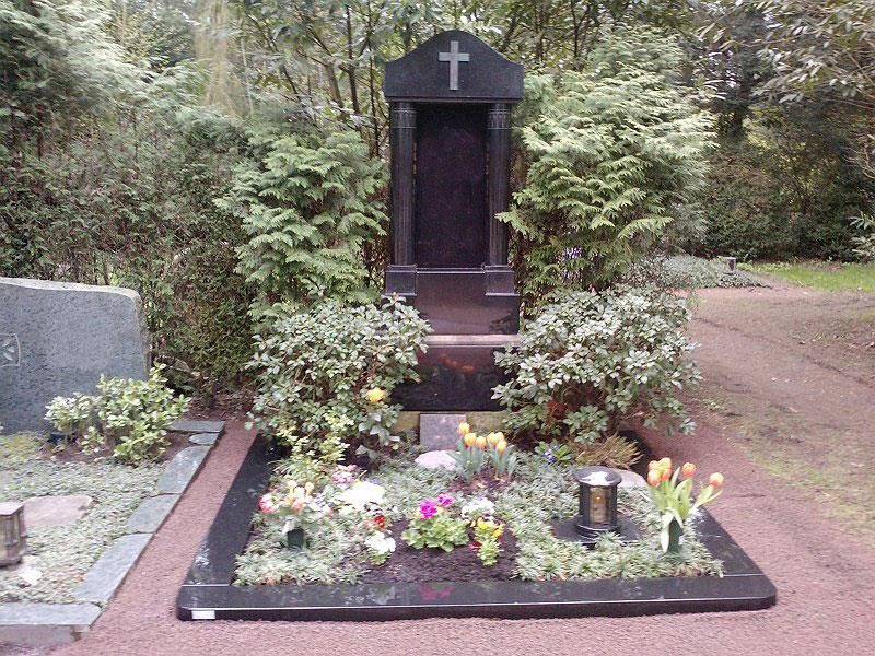 Ein Grab mit Blumen und einem Kreuz darauf