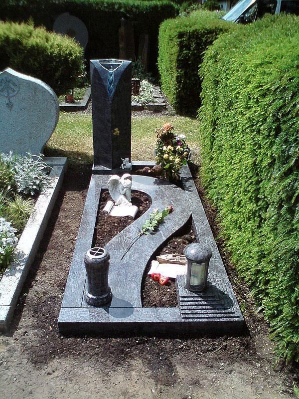 Ein Grab auf einem Friedhof mit Blumen und einer Laterne