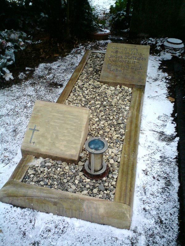 Ein Grab mit Kies und einem Kreuz darauf