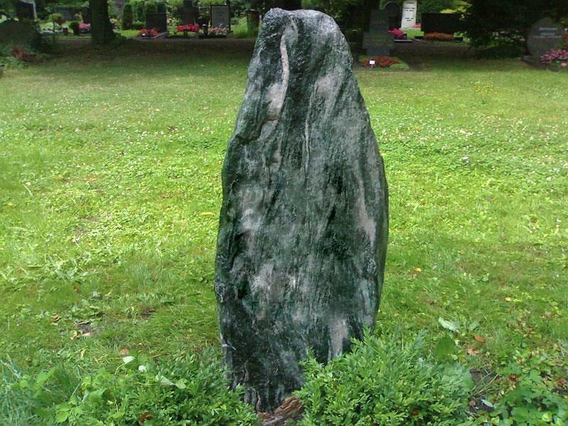 Ein großer Fels liegt mitten auf einem Grasfeld.