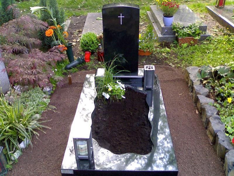 Ein schwarzer Grabstein mit einem Kreuz darauf auf einem Friedhof