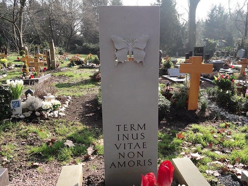 Ein Grabstein auf einem Friedhof, auf dem steht: „Ende des Lebens, nicht der Liebe“.