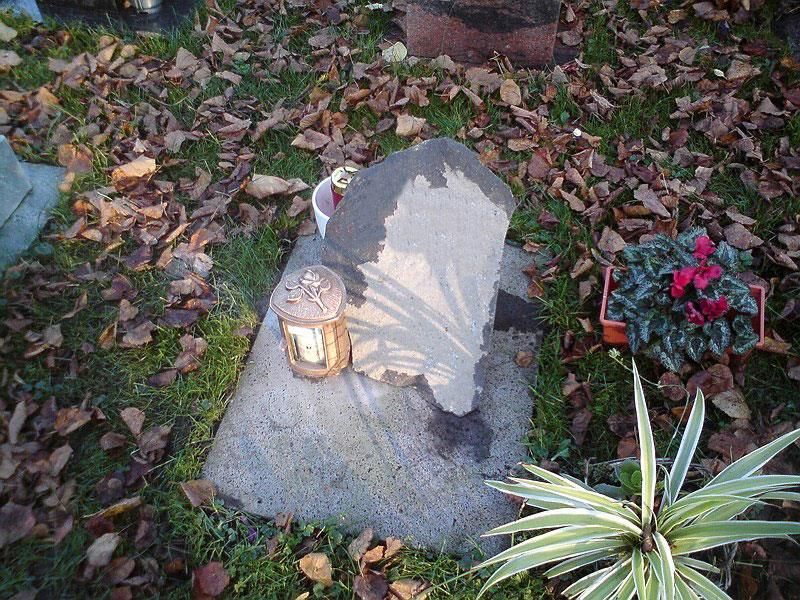 Ein Grab mit einer Laterne und Blumen auf einem Friedhof.