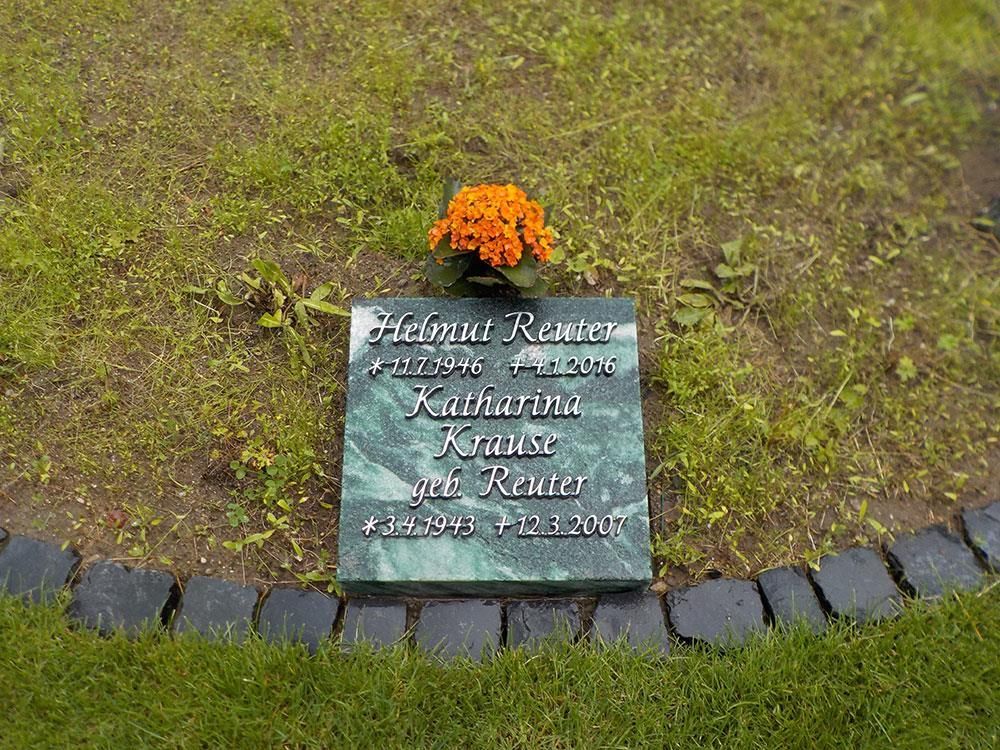 Ein Grabstein mit einer Blume darauf auf einem Friedhof.