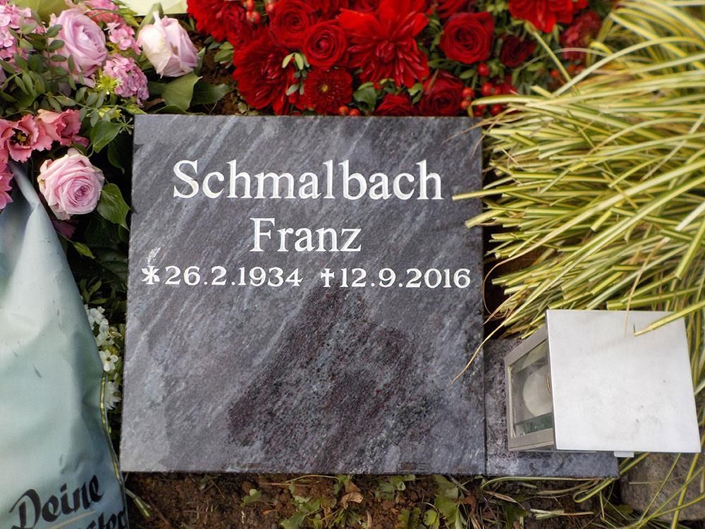 Ein Grabstein  ist von Blumen umgeben