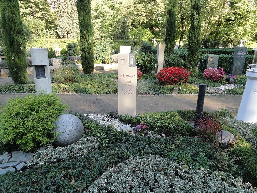 Auf einem Grab auf einem Friedhof steht ein Kreuz