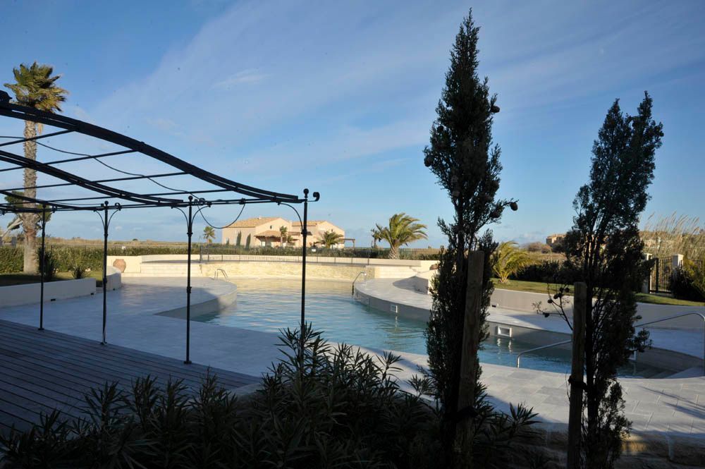 Pergola en fer forgé sur une terrasse devant une piscine