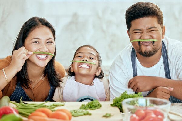 Una familia está sentada en una mesa con verduras en la boca.