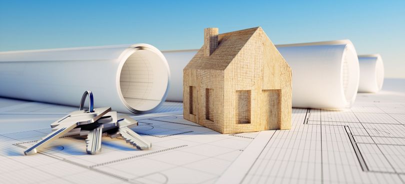 Une maquette de maison repose sur des plans architecturaux.