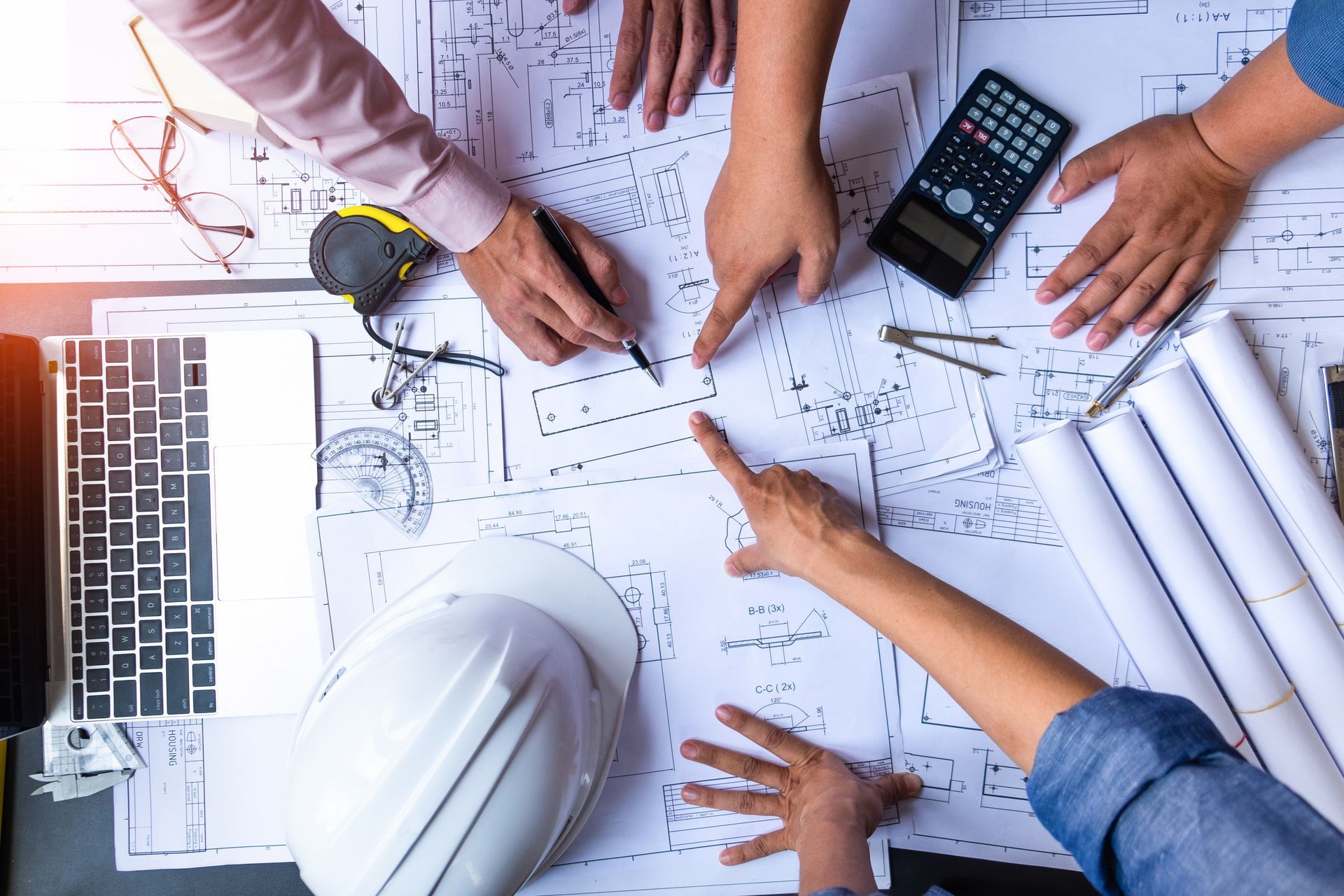 Vue aérienne de mains de personnes désignant des plans de construction.