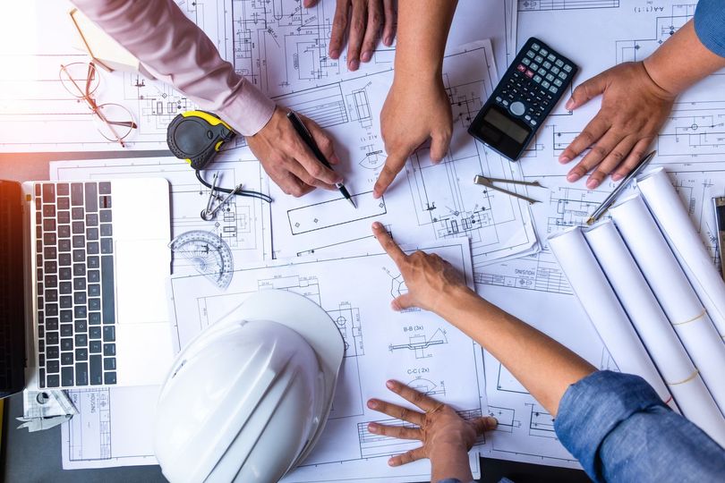 Vue aérienne de mains de personnes désignant des plans de construction.