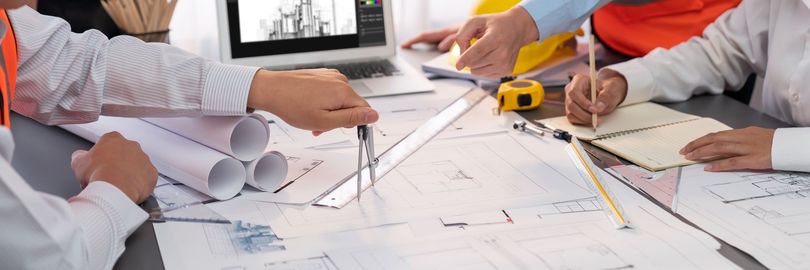 Vue aérienne de mains de personnes désignant des plans de construction.