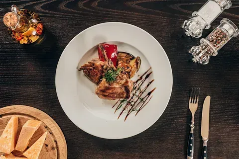 Un plato blanco cubierto con carne y verduras sobre una mesa de madera.