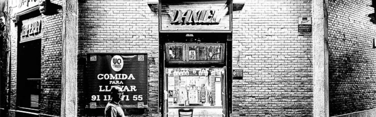 Una foto en blanco y negro de un edificio de ladrillo con un cartel que dice comida.