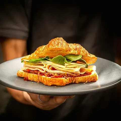 Una persona sostiene un plato con un sándwich encima.