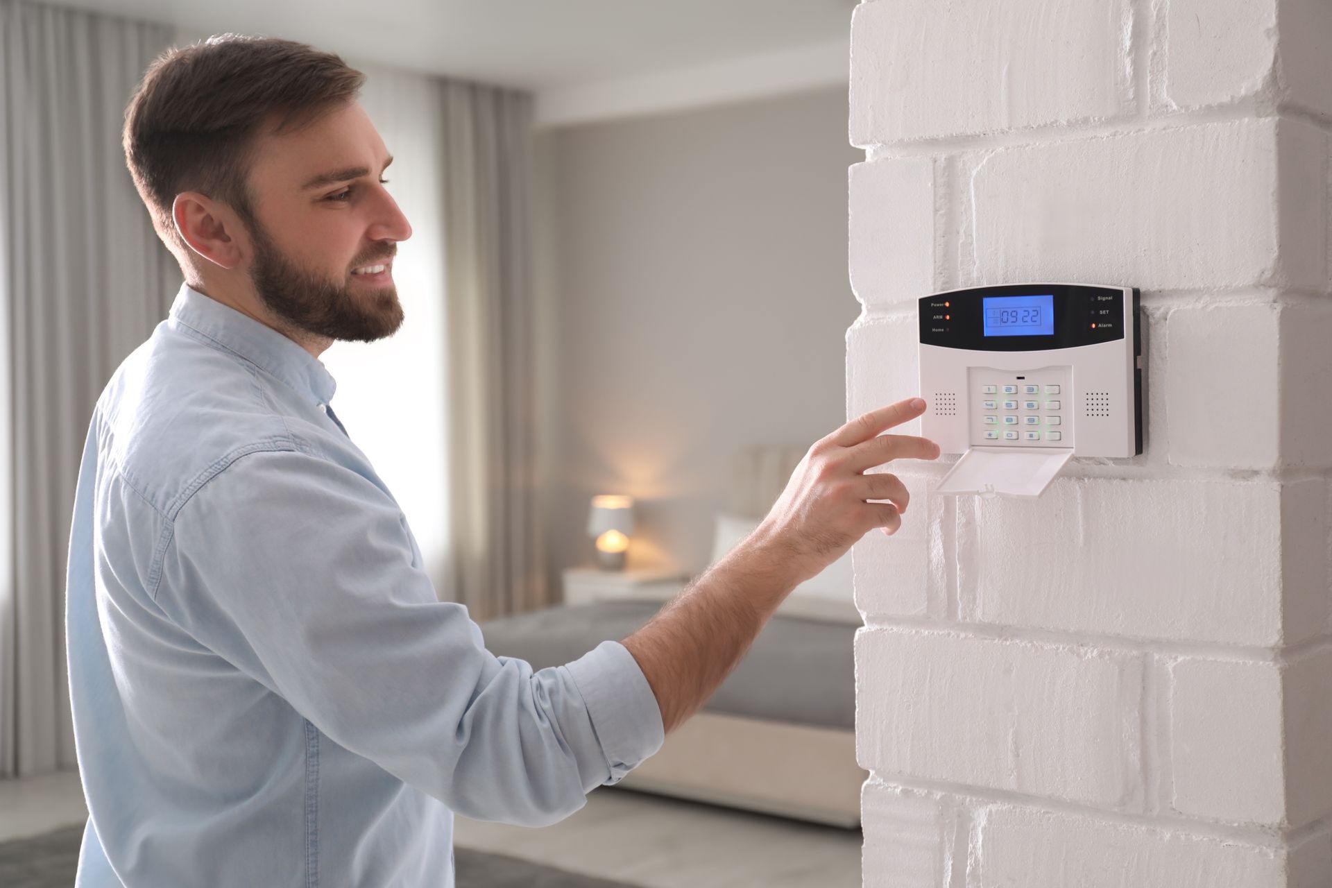 Un homme utilisant le boîtier de commandes d'alarme de son habitation.