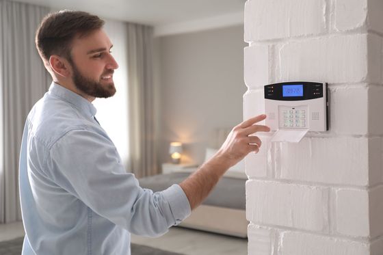 Un homme utilisant le boîtier de commandes d'alarme de son habitation.