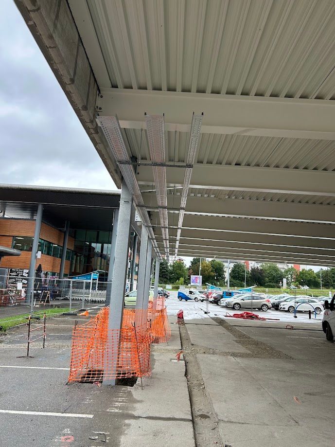 Trois passages en métal pour câblage électrique accrochés au plafond le long d'un parking protégé