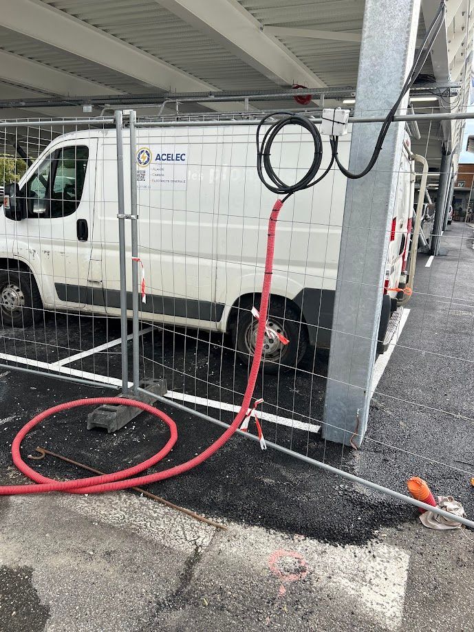 Camionnette de chez ACELEC garée sur un parking derrière une grille