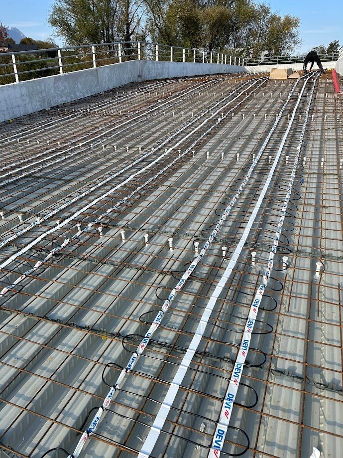 Câbles électriques en zigzag sous une grille, avant création d'une chape de béton