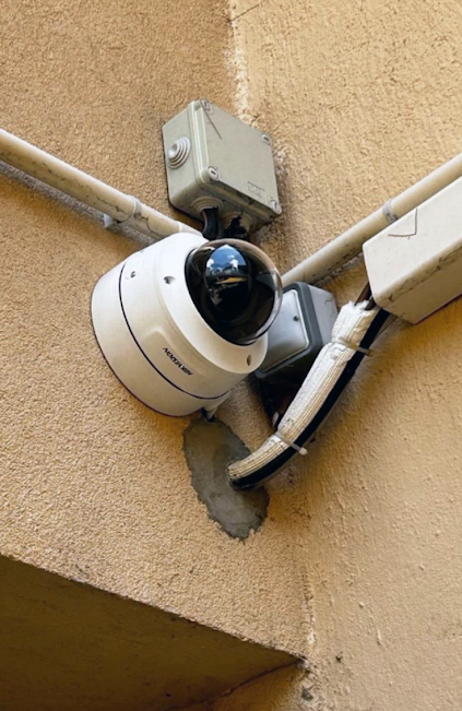 Caméra de sécurité extérieure accrochée en haut d'un mur.
