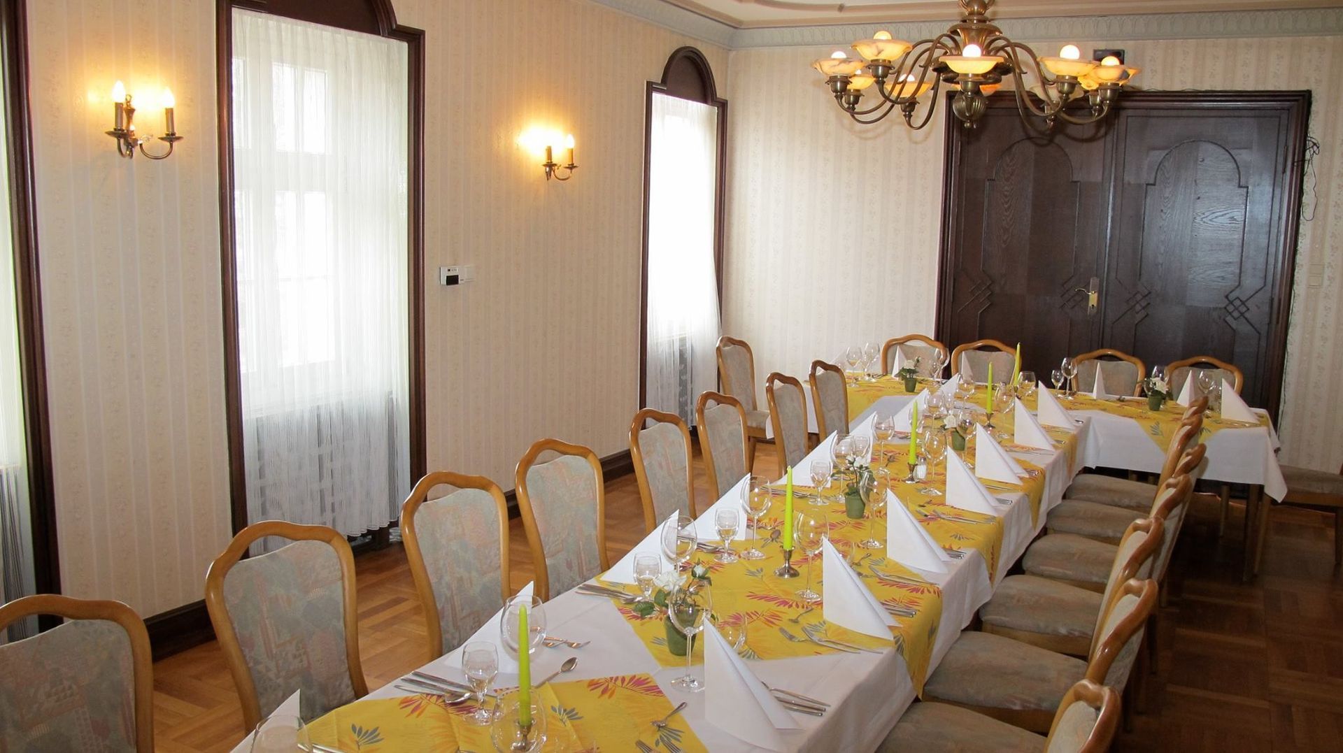 A long table in a room with yellow and white tables and chairs