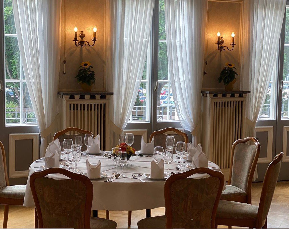 A dining room with a round table and chairs set for a meal.
