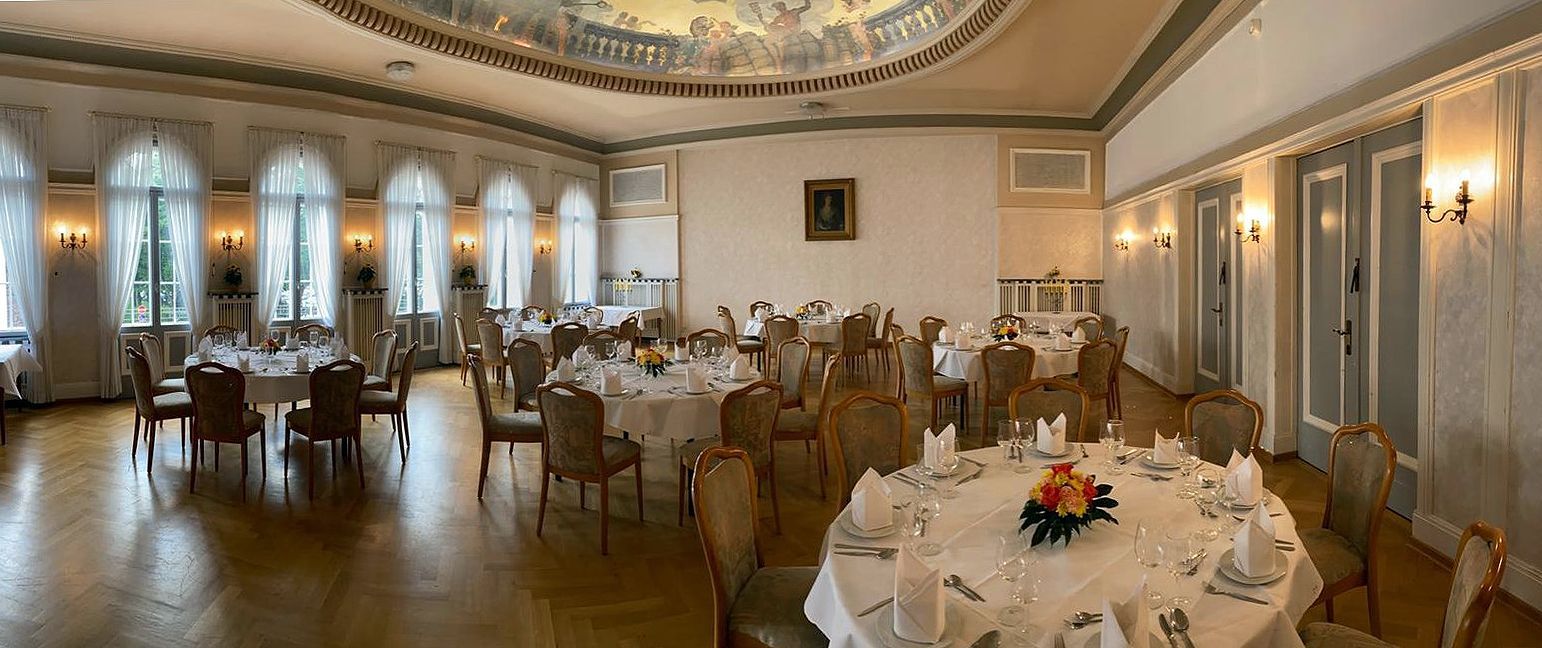 Un gran salón con mesas y sillas preparadas para un banquete.