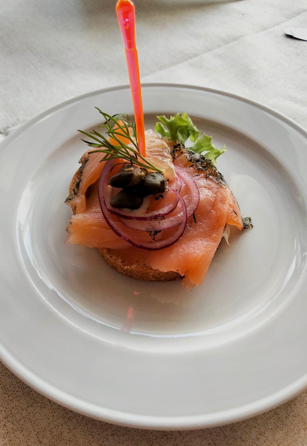 Ein weißer Teller mit geräuchertem Lachs, Zwiebeln und Oliven