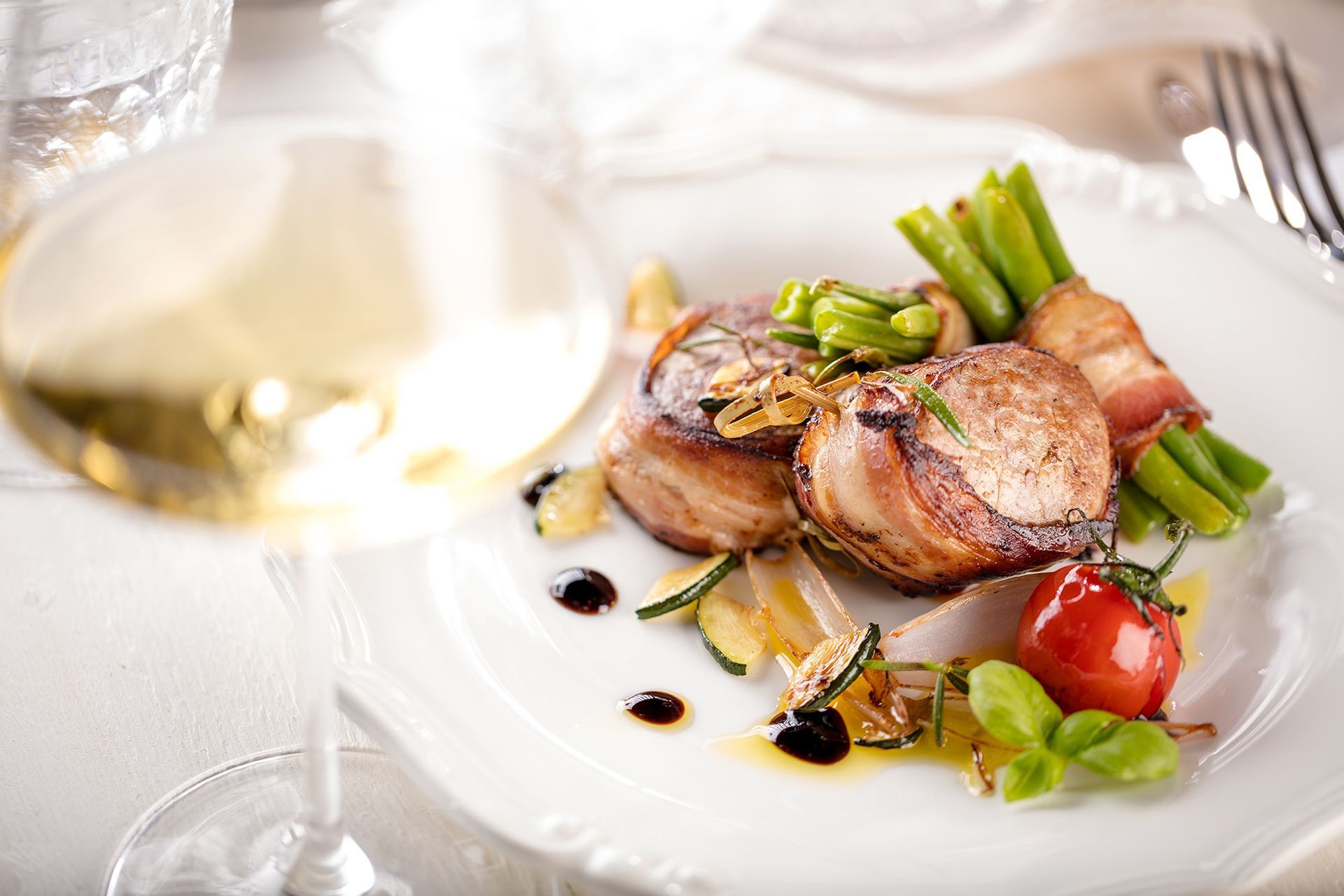 Ein Teller mit Essen und ein Glas Wein auf einem Tisch.