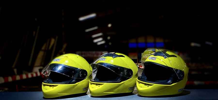 Auf einem Tisch liegen drei gelbe Motorradhelme.
