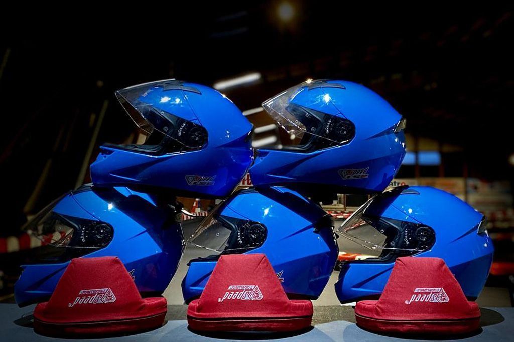 Drei blaue Motorradhelme liegen übereinander gestapelt auf einem Tisch.