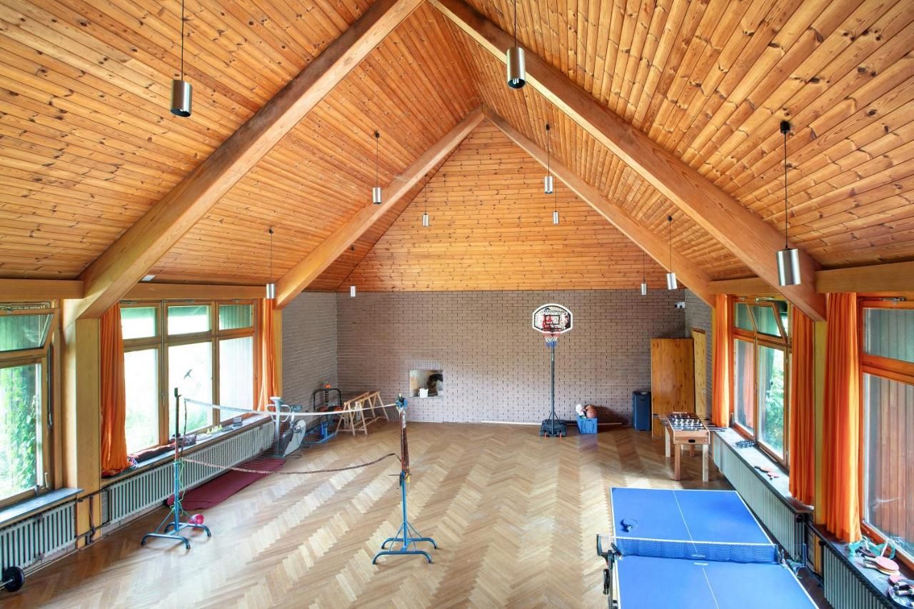 Ein großer Raum mit Holzdecke und zwei Tischtennisplatten