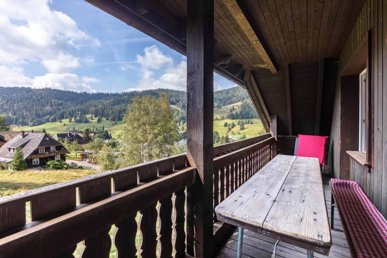Ein Holzbalkon mit Tisch und Stühlen mit Blick auf ein Tal.