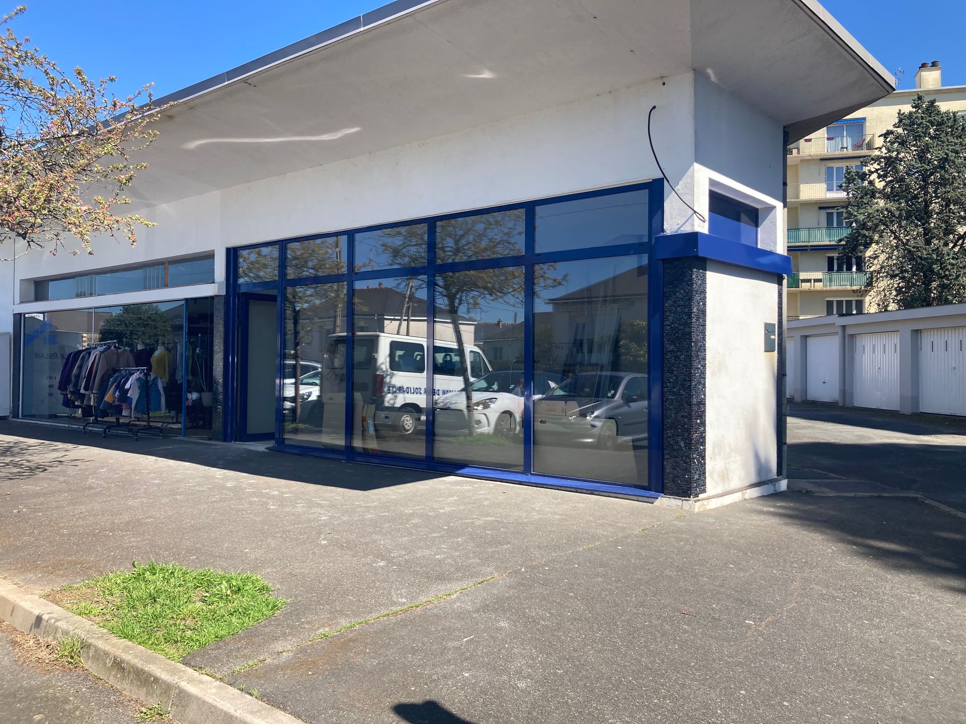 Extérieur d'un bâtiment commercial avec de grandes fenêtres reflétant les véhicules.