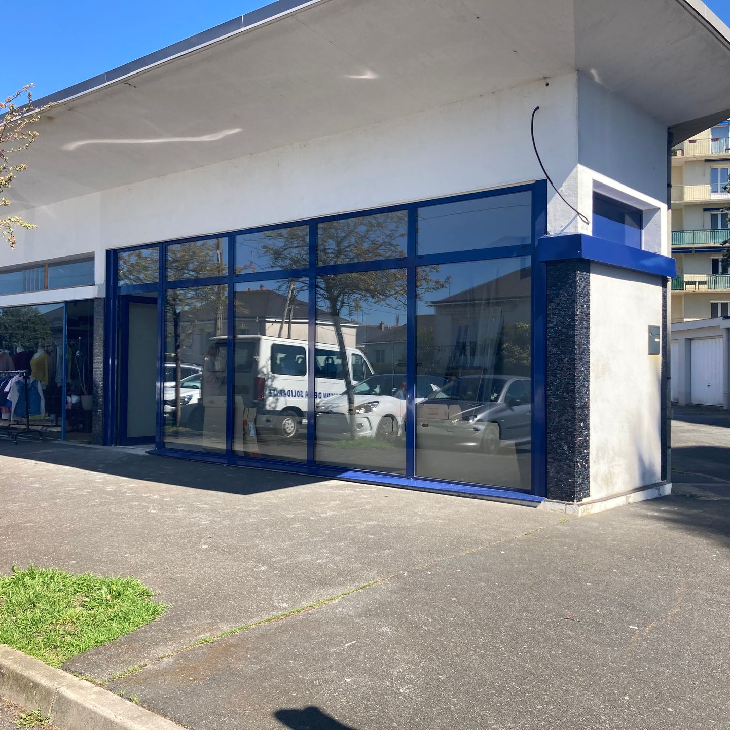 Extérieur d'un bâtiment commercial avec de grandes fenêtres reflétant les véhicules.