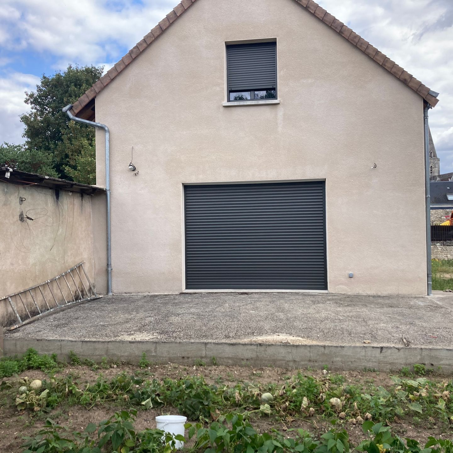 Volets roulants gris foncé sur une fenêtre et une baie vitrée d'une façade de maison.