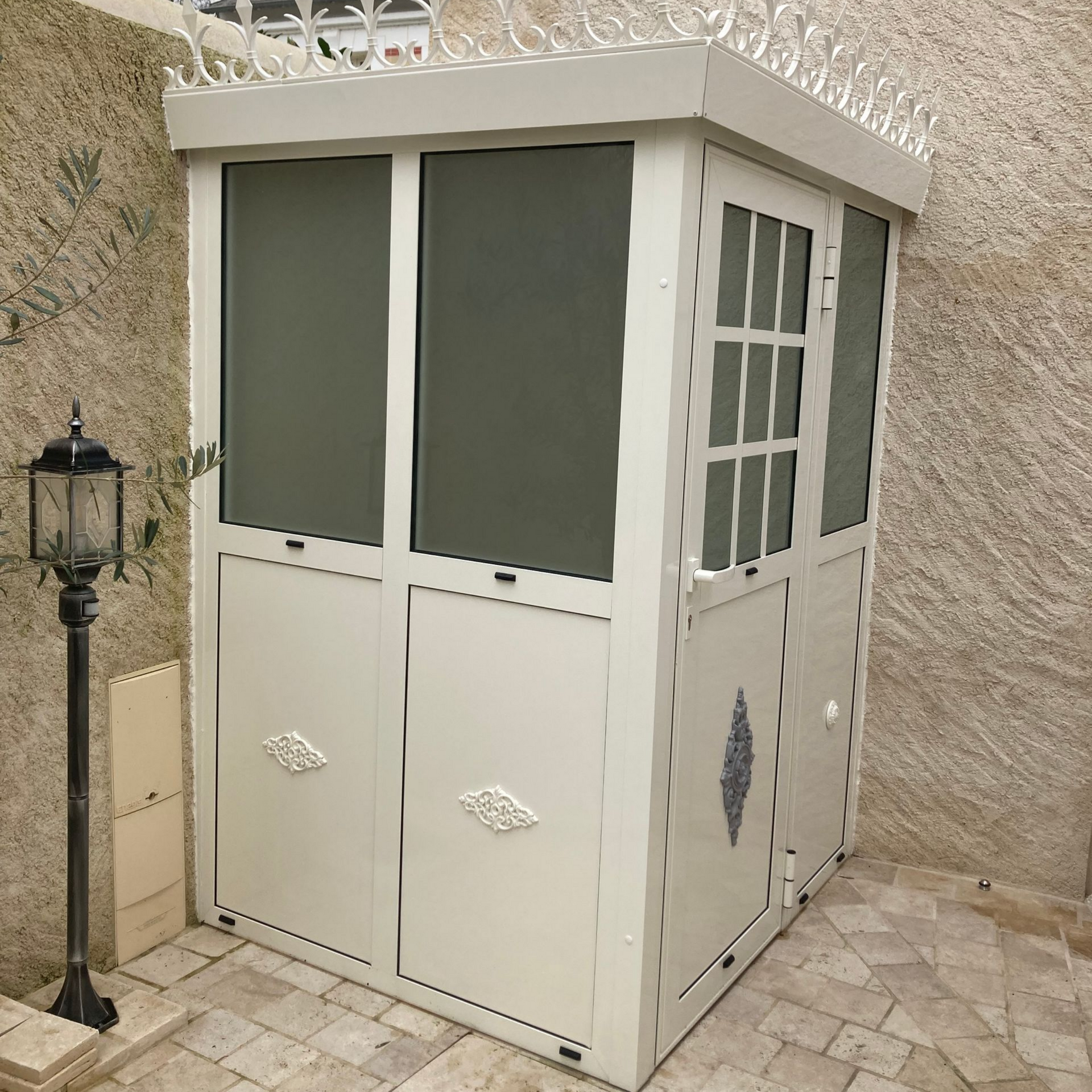 Petit abri en aluminium blanc dans le coin d'une cour.