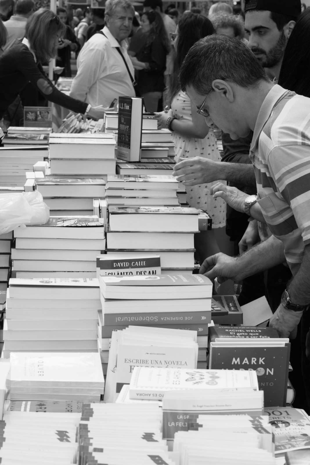 Personas mirando y seleccionando libros en una feria del libro al aire libre.