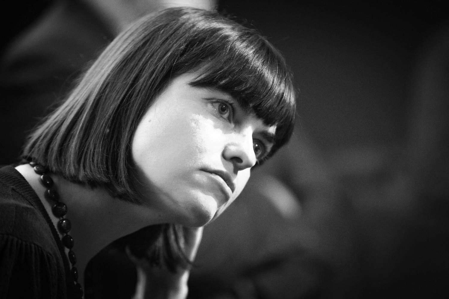 Mujer con corte bob oscuro y flequillo, mirando a un lado, con un top oscuro y un collar de cuentas. Foto en blanco y negro.