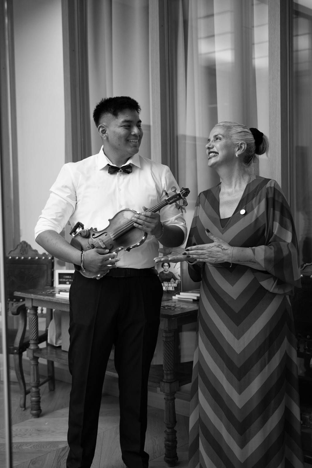 Hombre sentado en un escenario, leyendo un libro a una gran audiencia.