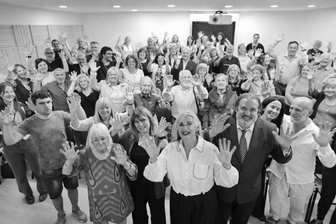 Personas sentadas en una biblioteca leyendo y conversando cerca de estanterías.