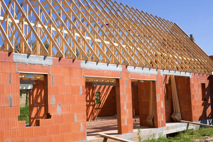 Maison en briques partiellement construite avec charpente en bois en construction