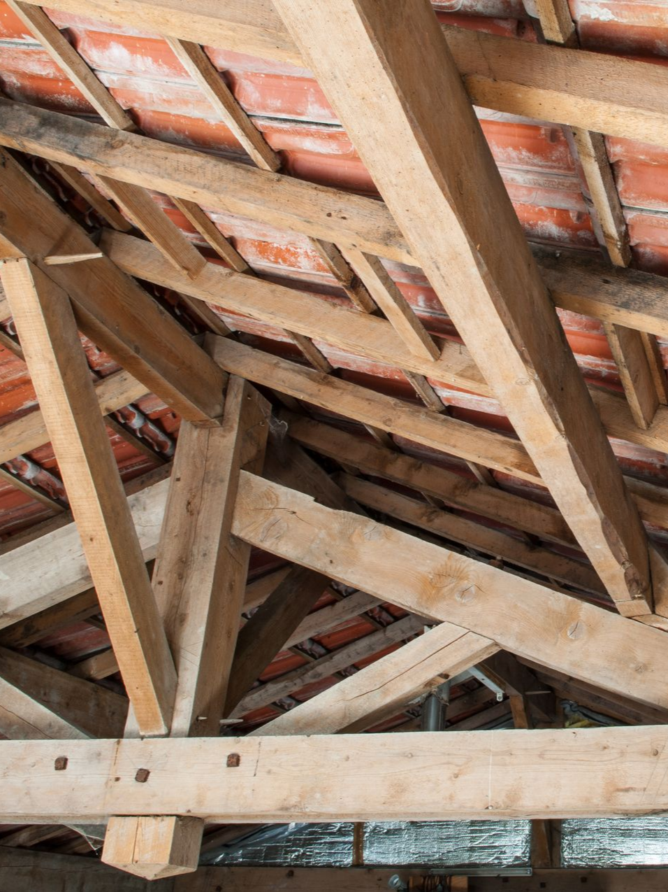Charpente en bois avec tuiles de briques apparentes vue d'en bas, montrant la structure du grenier