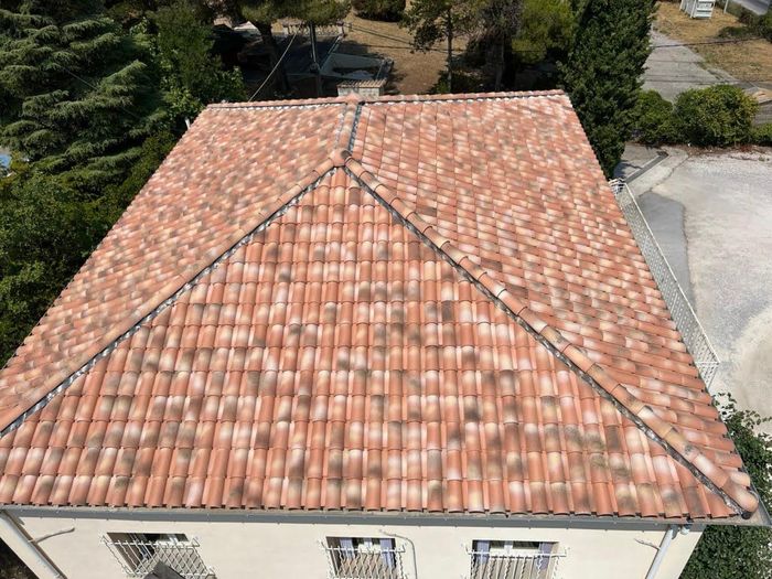 Vue aérienne d'une maison au toit de tuiles rouges, avec des arbres et une allée à proximité